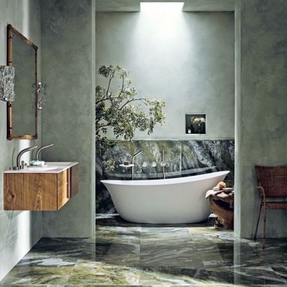 Luxe bathroom with green marble floor, wooden wall-hung vanity and modern white freestanding bath