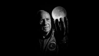 Portrait of Al Worden holding an illuminated moon