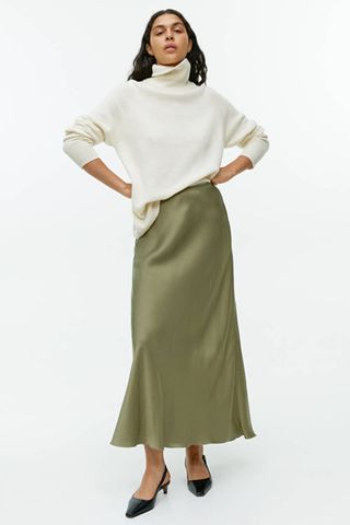 arket sale - woman wearing green slip skirt and cream knit