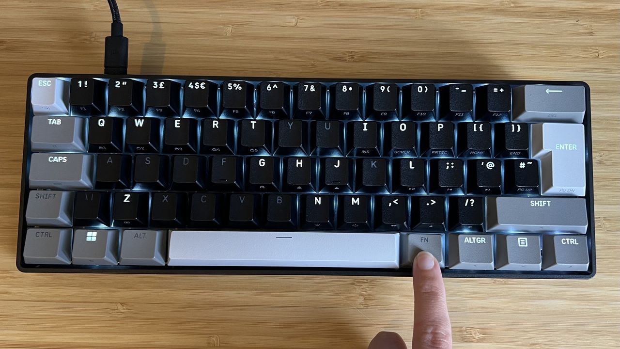 Finger holding down function key on Corsair Clipper Pro Mini 60 to show dual-function LEDs