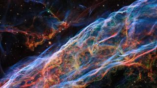 a huge, colorful tube of gas and dust snakes through the blackness of deep space in this hubble space telescope photo.