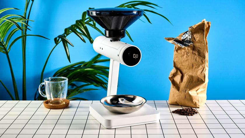 the acaia orion coffee bean doser is a white sci-fi-inspired bean doser with a rotating dial and LED screen and a bean hopper photographed against a blue tom&#039;s guide background