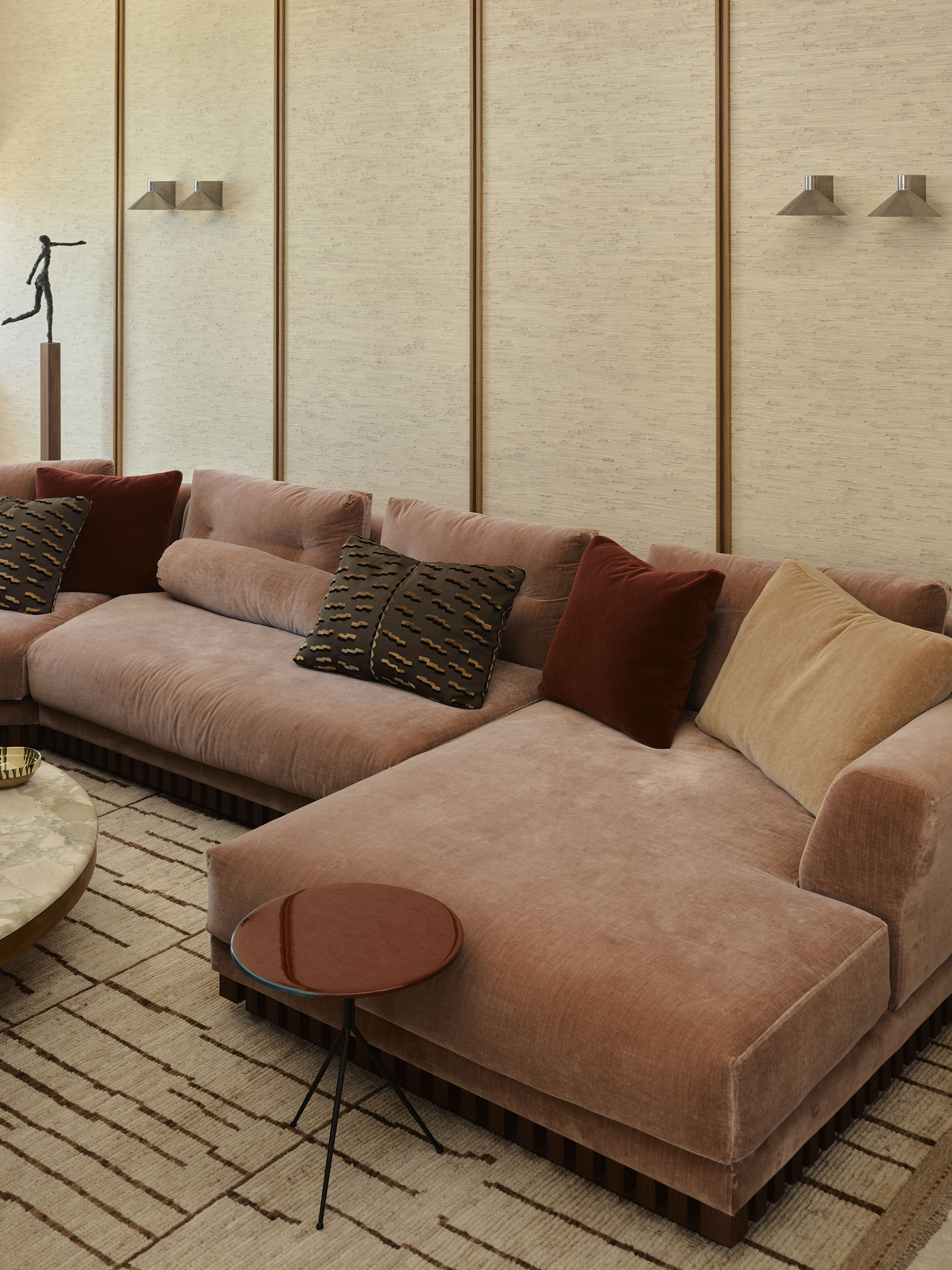 A peige velvet sofa in a contemporary living room, with textured rug, marble coffee table and lacquer side table