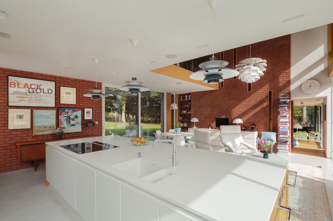 open plan kitchen, dining and living space with brick wall