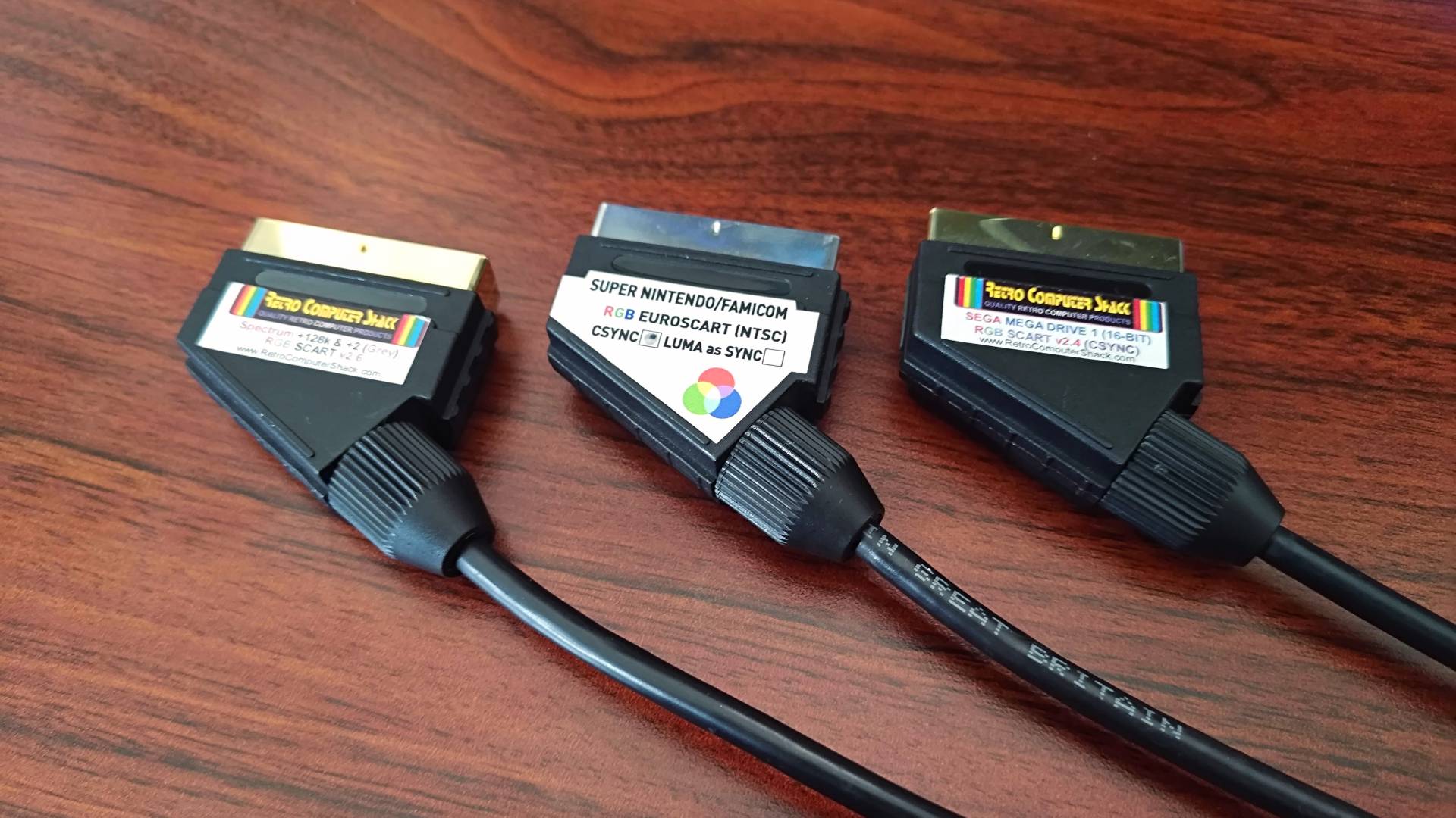 RGB SCART cables by Retro Computer Shack and Retro Gaming Cables on woodgrain desk.