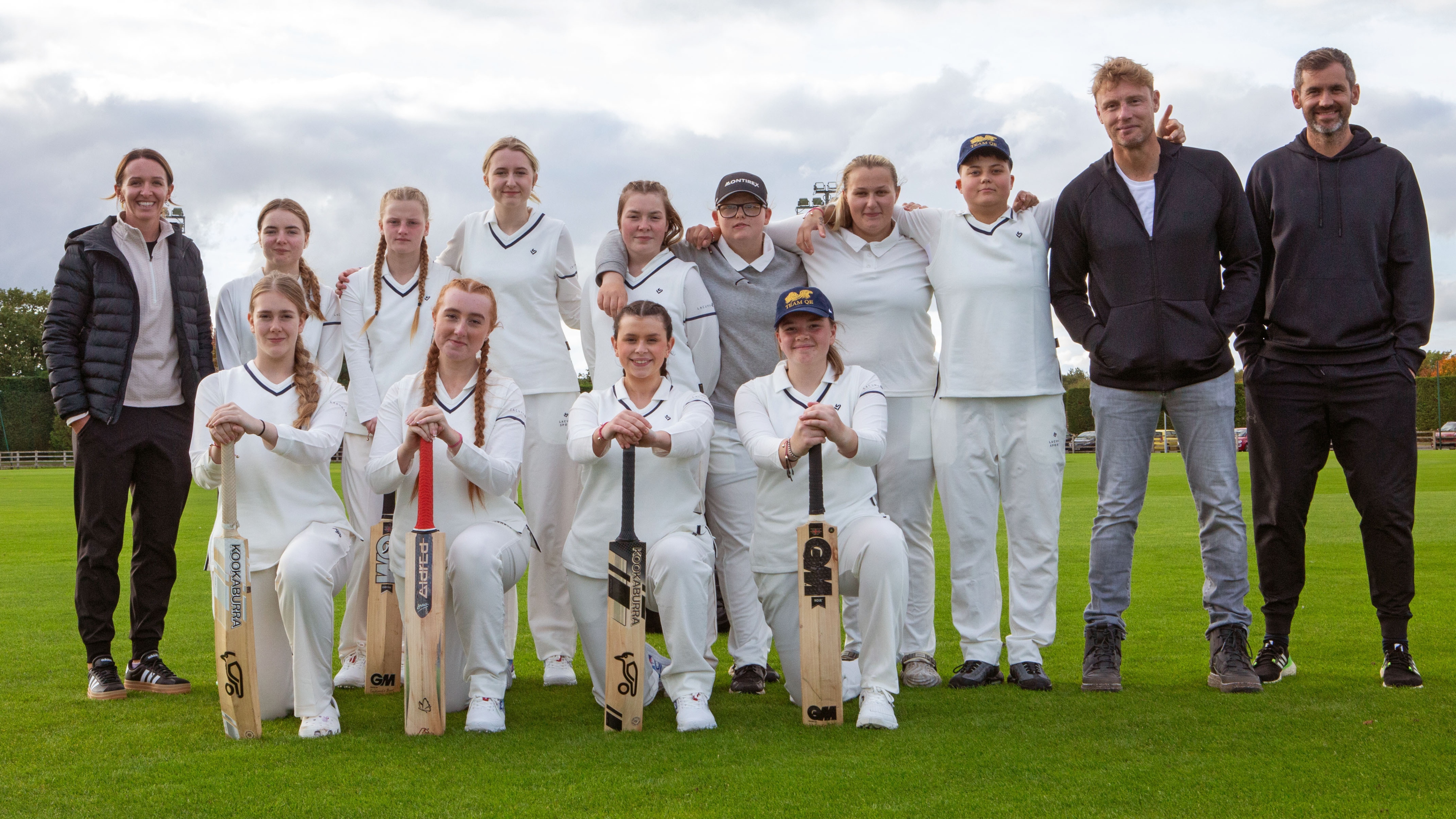 People: Kate Cross, Carla, Madi, Milla, Summer, Mollie, Katie, Madi, Genna, Aimee, Matilda, Evie Freddie Flintoff, Kyle Hogg in cricket whites and smiling for the camera in a team line up