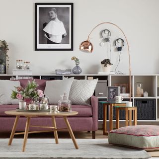 living area with white wall and shelves and pink sofa with cushions and coffee table