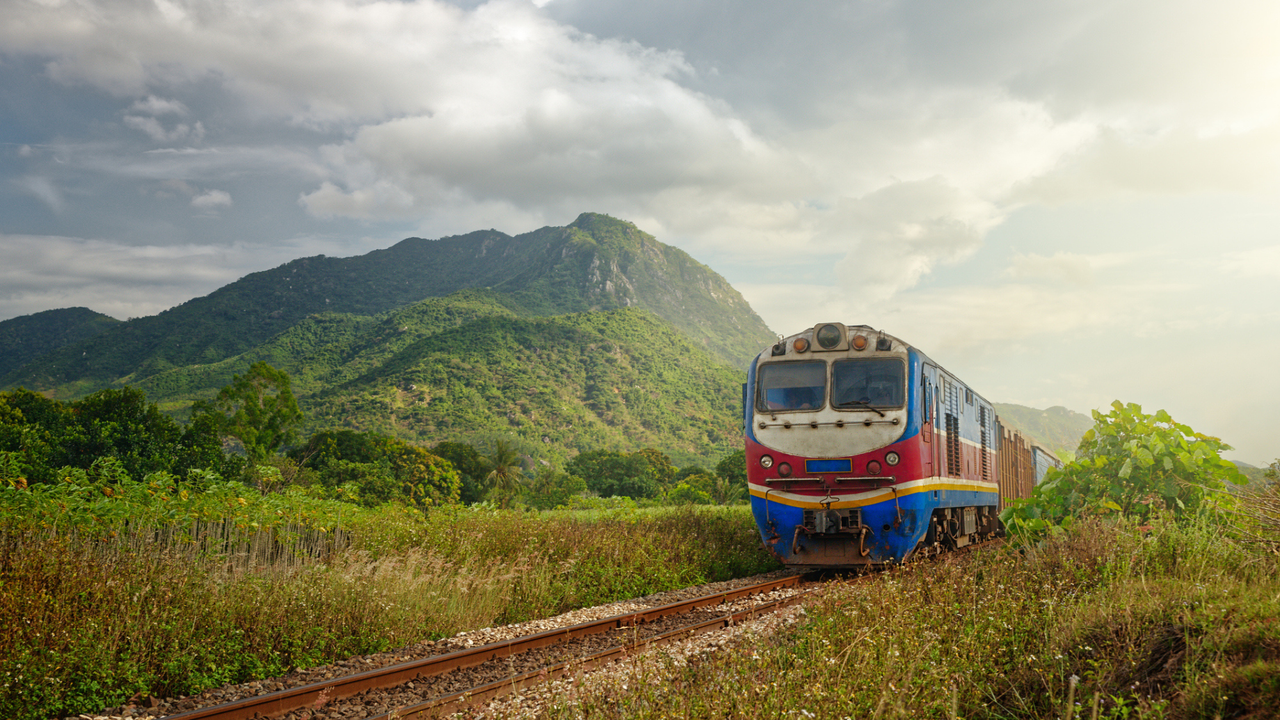 Blue-red locomotive passing at sunset against a backdrop of beautiful landscape