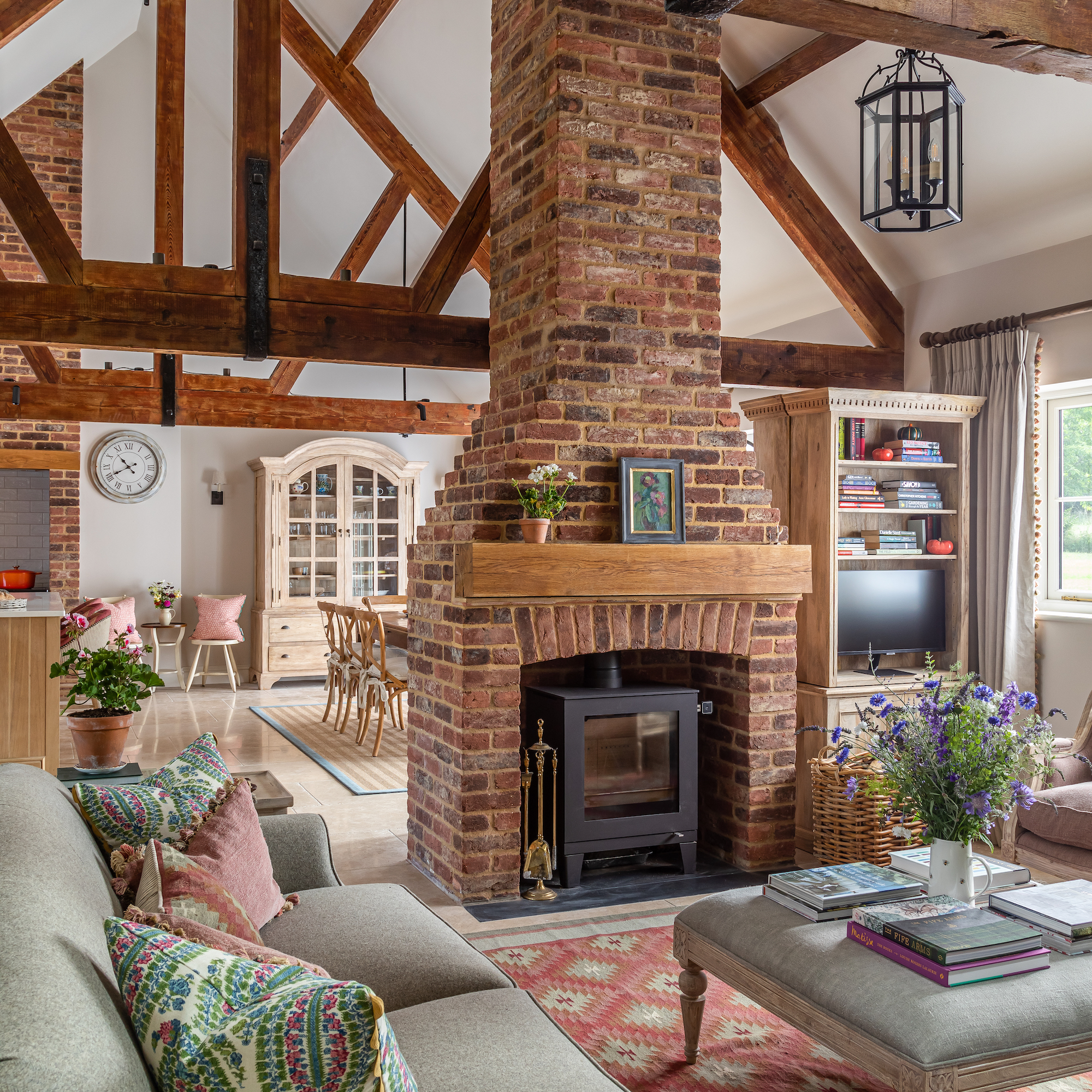 sitting area in barn conversion with large brick fireplace with woodburner stove