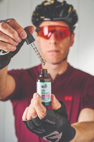 A cyclist holding a bottle of CBD oil