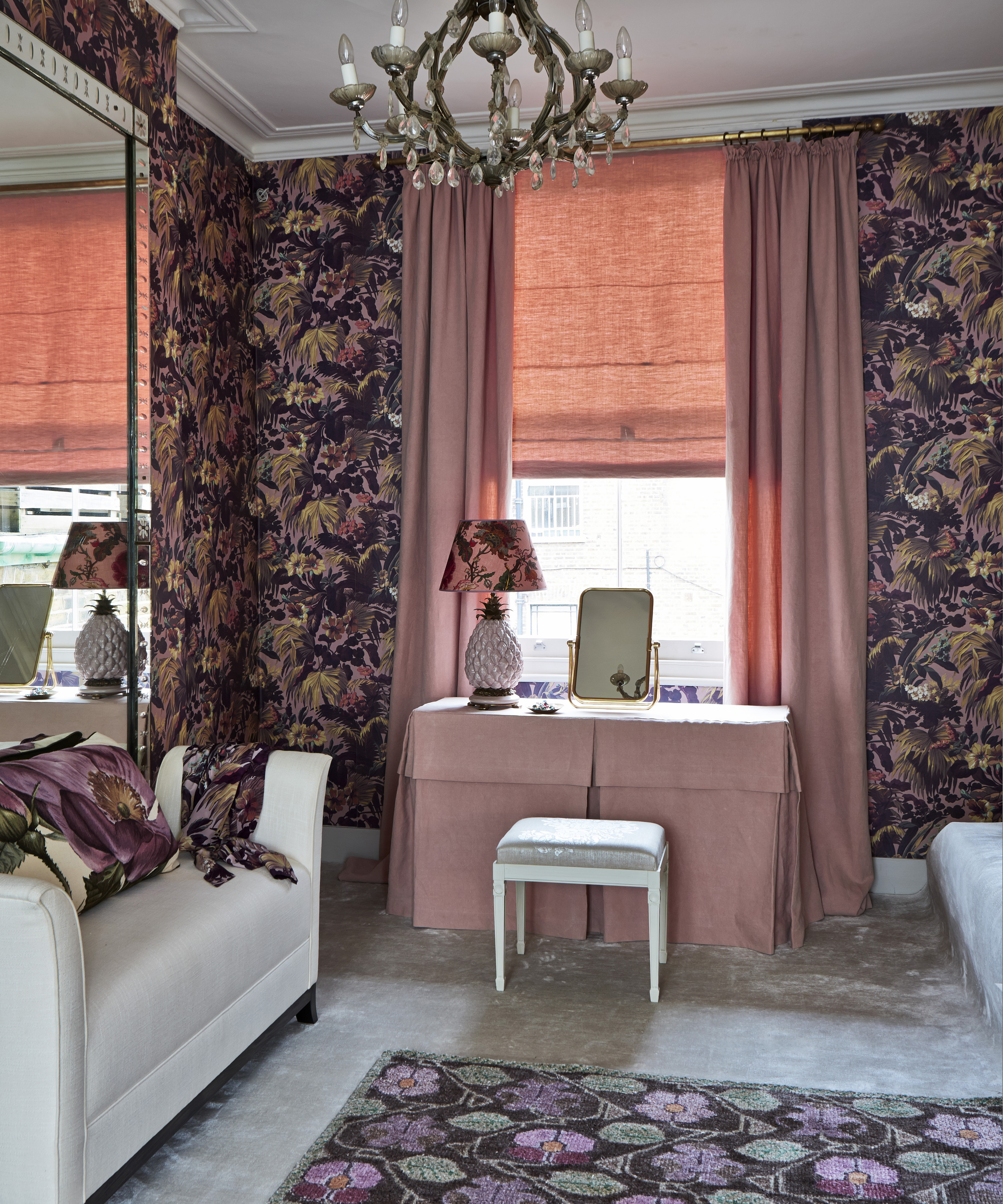 A bedroom with a pink dressing table and black floral wallpaper
