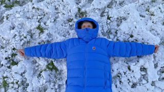 Man wearing Fjällräven Expedition Mid Winter Jacket while lying in snow