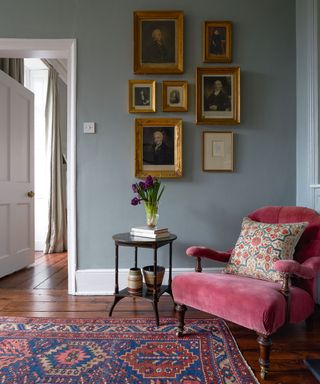 Grey painted entryway with wood flooring, pink chair and rug