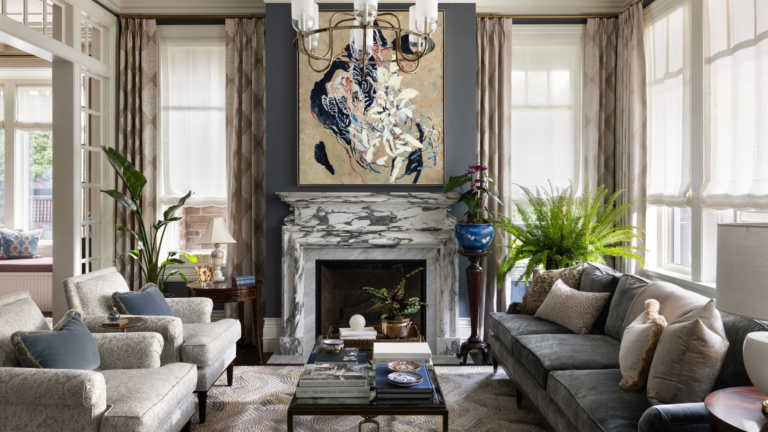 a traditional tudor-style living room with deep blue wall paint, lots of traditional windows, and a marble fireplace