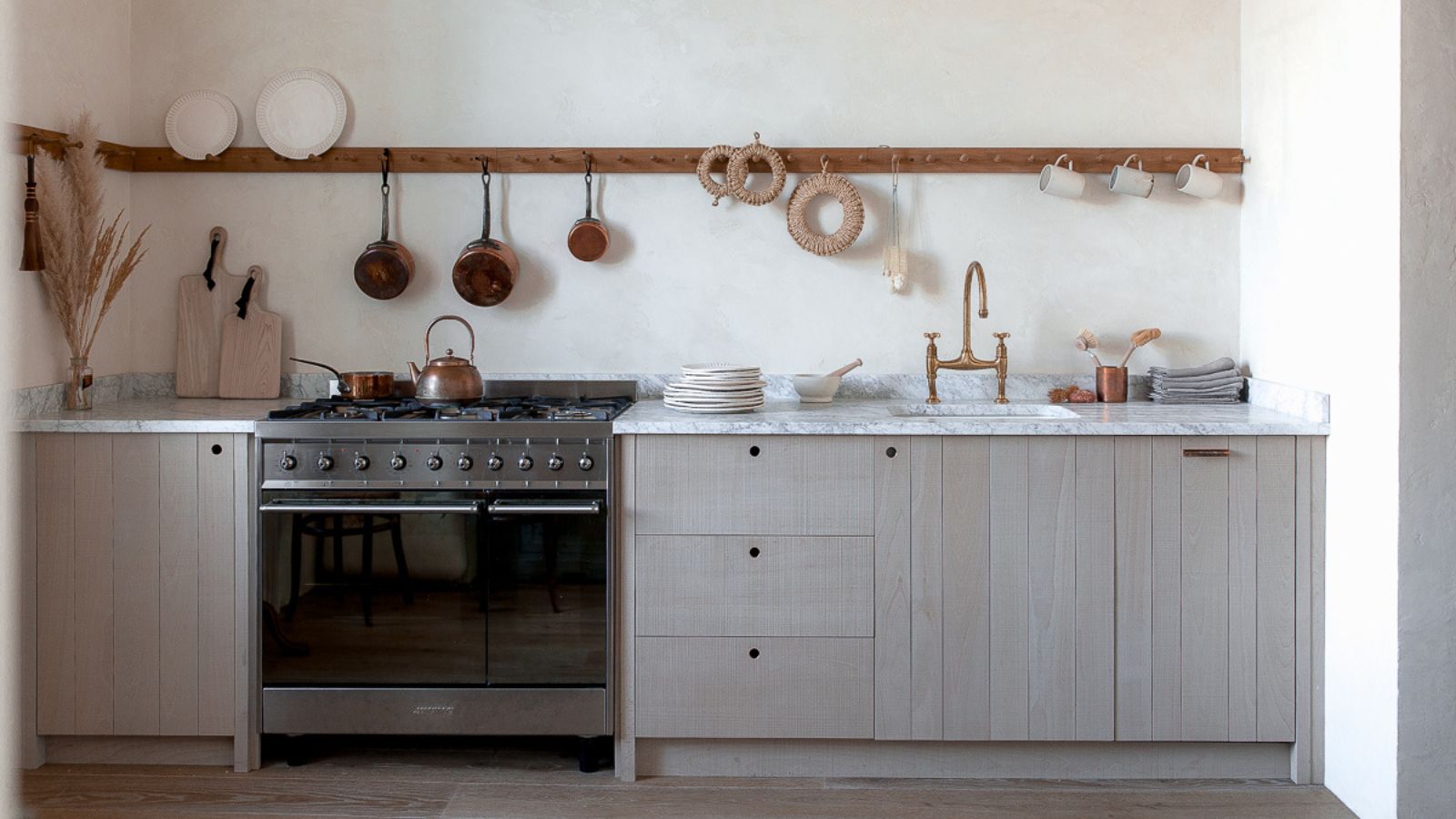 A wooden kitchen with marble counters and limewash walls