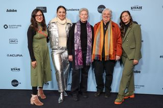 five woman pose in front of a step and repeat at a film festival