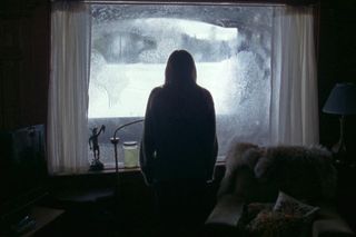 grace looks out the window in Richard Armitage movie The Lodge.