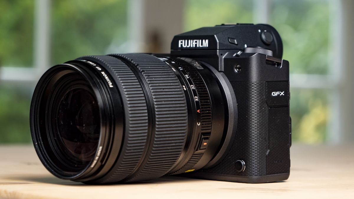 Front of the Fujifilm GFX100 II on a wooden table with lens attached
