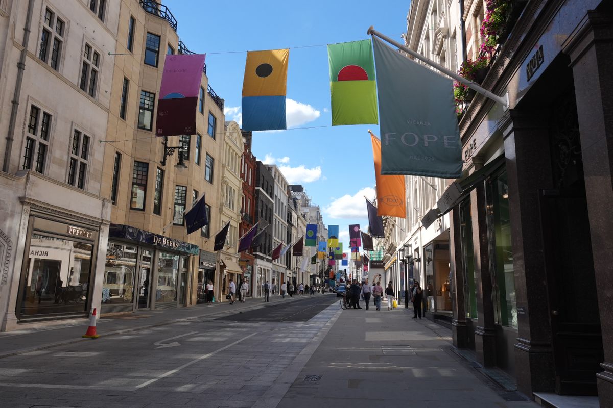 Bond Street in London lined with luxury stores and colorful banners suspended above the road.