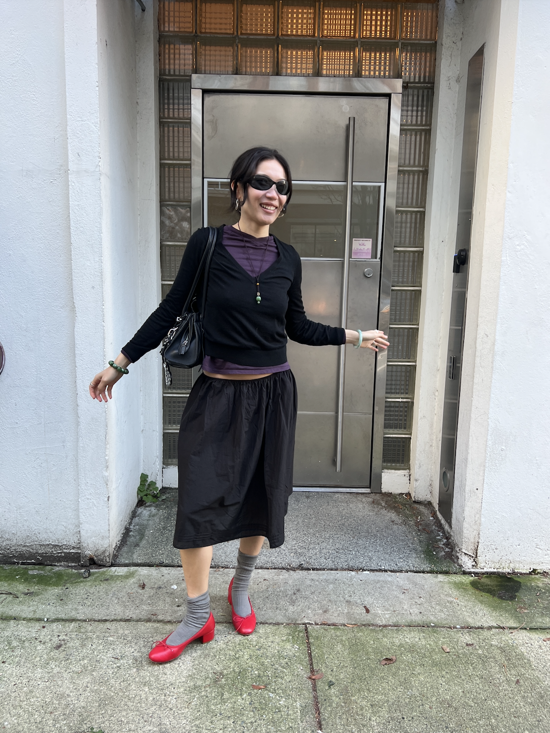 Vivian Li wearing a black outfit and black heels and gray socks