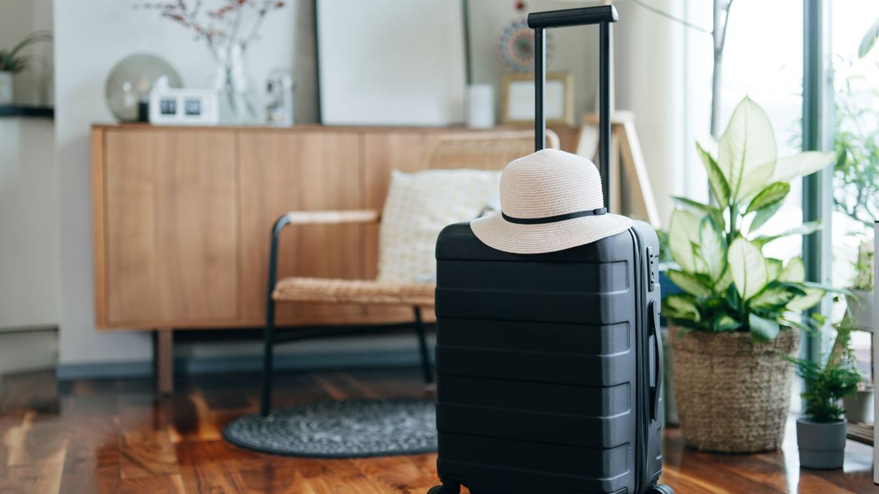 A suitcase in a bright living room with a straw hat