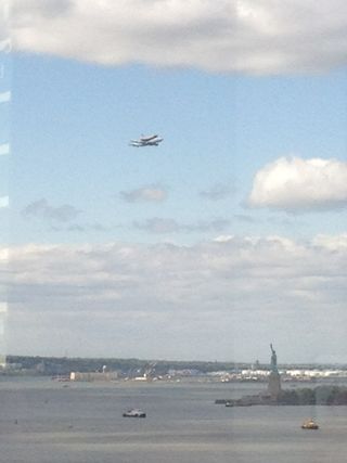 The space shuttle Enterprise flies over the Statue of Liberty.