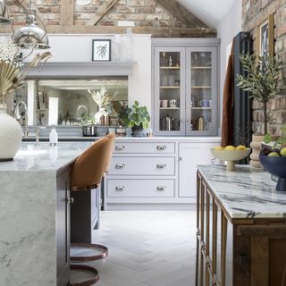 grey kitchen with glass cabinet doors and marble tops and herringbone wood floors