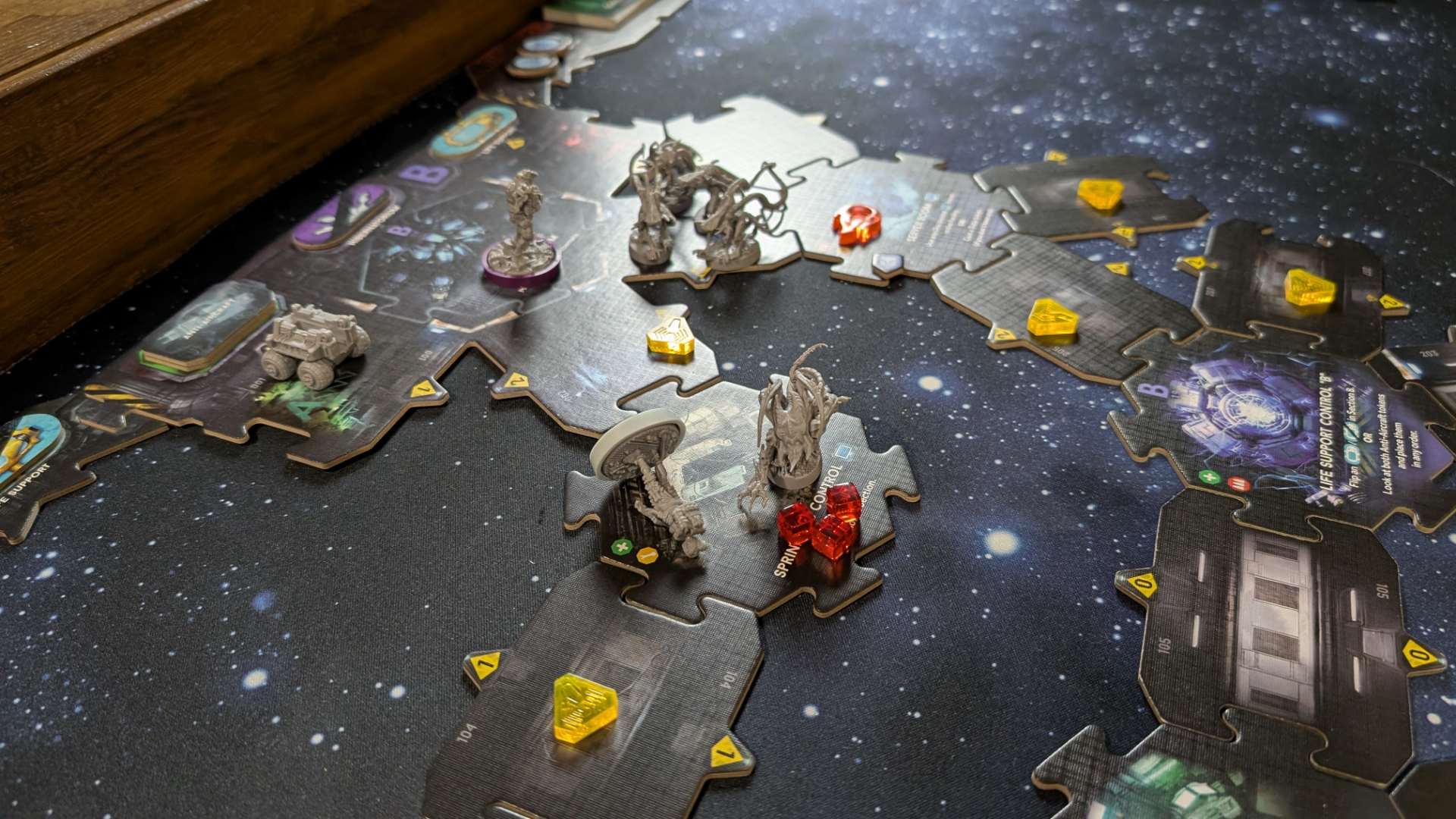 Nemesis: Retaliation pieces, board tiles, and tokens on a gaming table with a starry effect