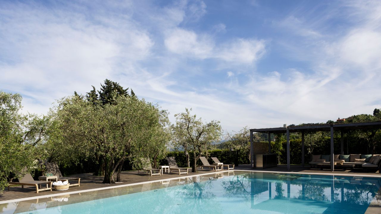 swimming pool with decking, pergola and sun loungers in italy