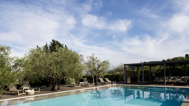 swimming pool with decking, pergola and sun loungers in italy