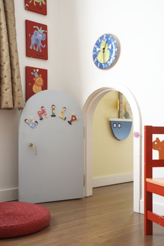 A children's bedroom with a tiny custom built arched doorway leading into the next room