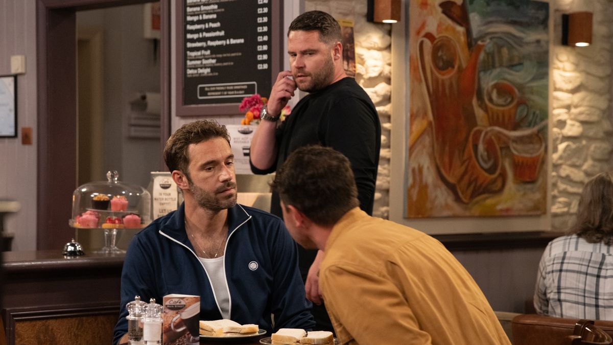 Aaron Dingle looks annoyed at John Sugden on a date with another man in the cafe.