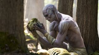 Jacob Elordi as the creature holding up skull in a forest 