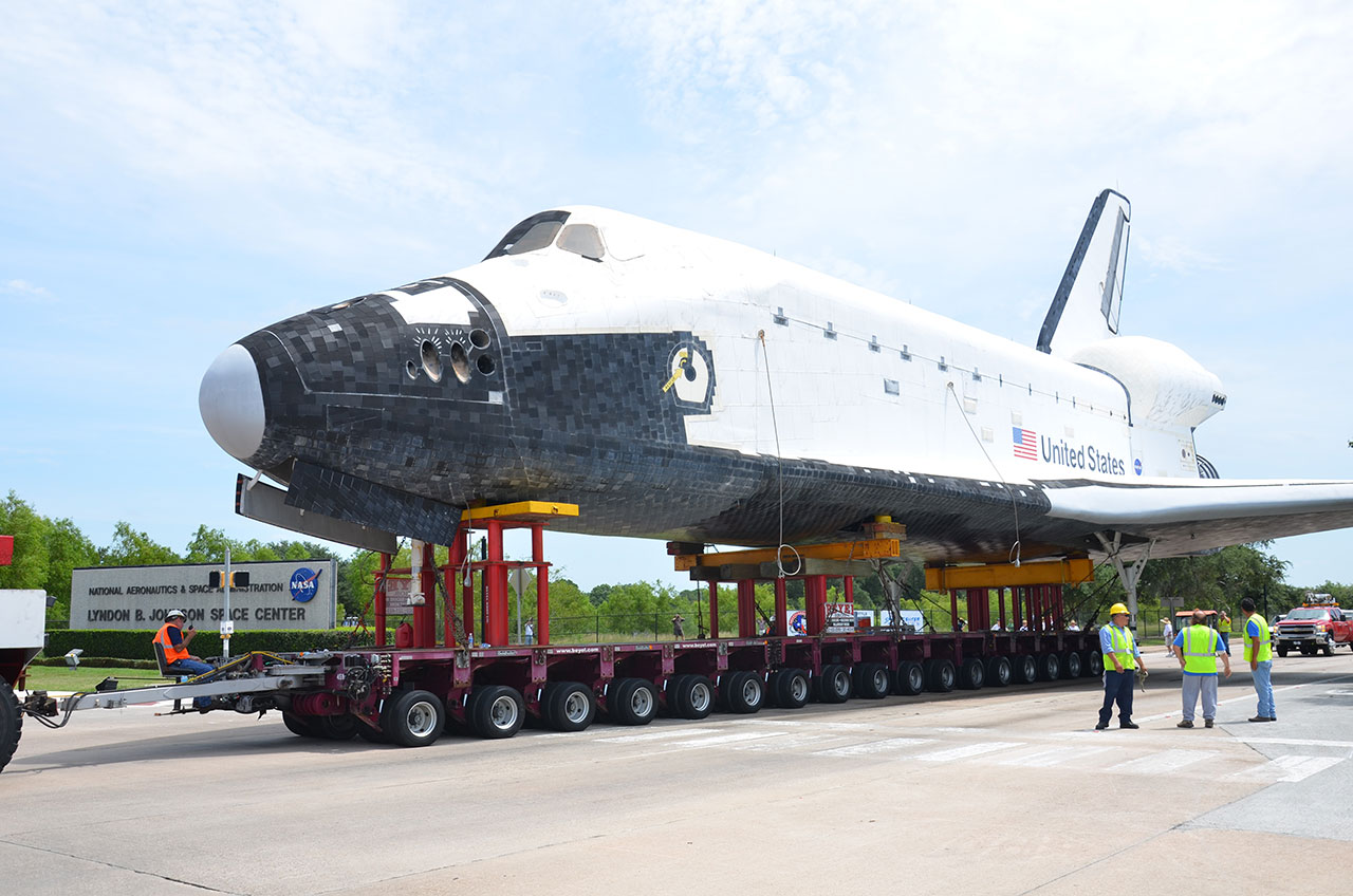 A high-fidelity replica space shuttle passes by the entrance sign to NASA’s Johnson Space Center, on its way to the center’s official visitor attraction, Space Center Houston, on June 3, 2012.