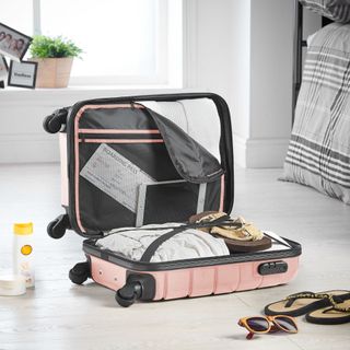 An open, pink luggage case with its contents on display