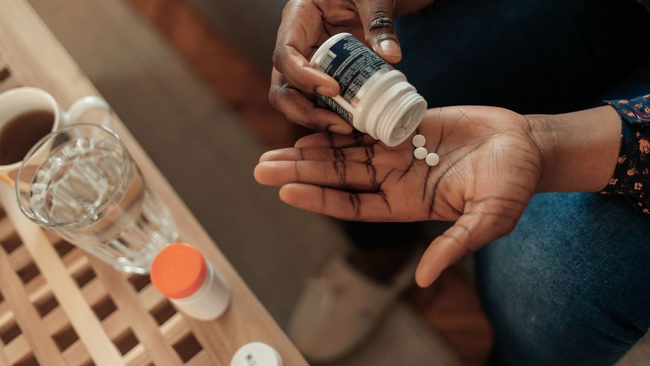 Woman dispensing vitamins from a bottle into her palm