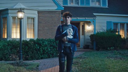 Teen stands on a driveway at night holding a white rabbit in Agatha All Along