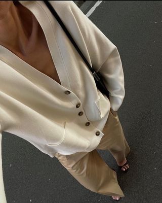 @anoukyve wearing beige trousers with a white cardigan