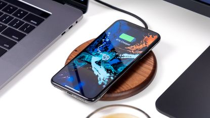 Best wireless chargers 2023: image depicts smartphone on wooden disc wireless charging pad