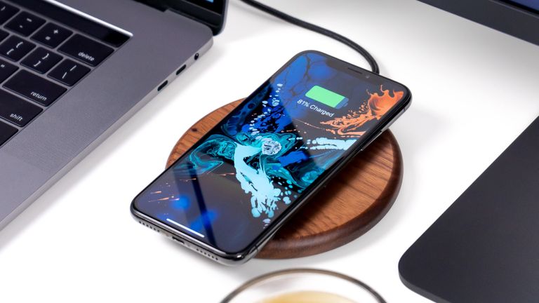 Best wireless chargers 2022: image depicts smartphone on wooden disc wireless charging pad