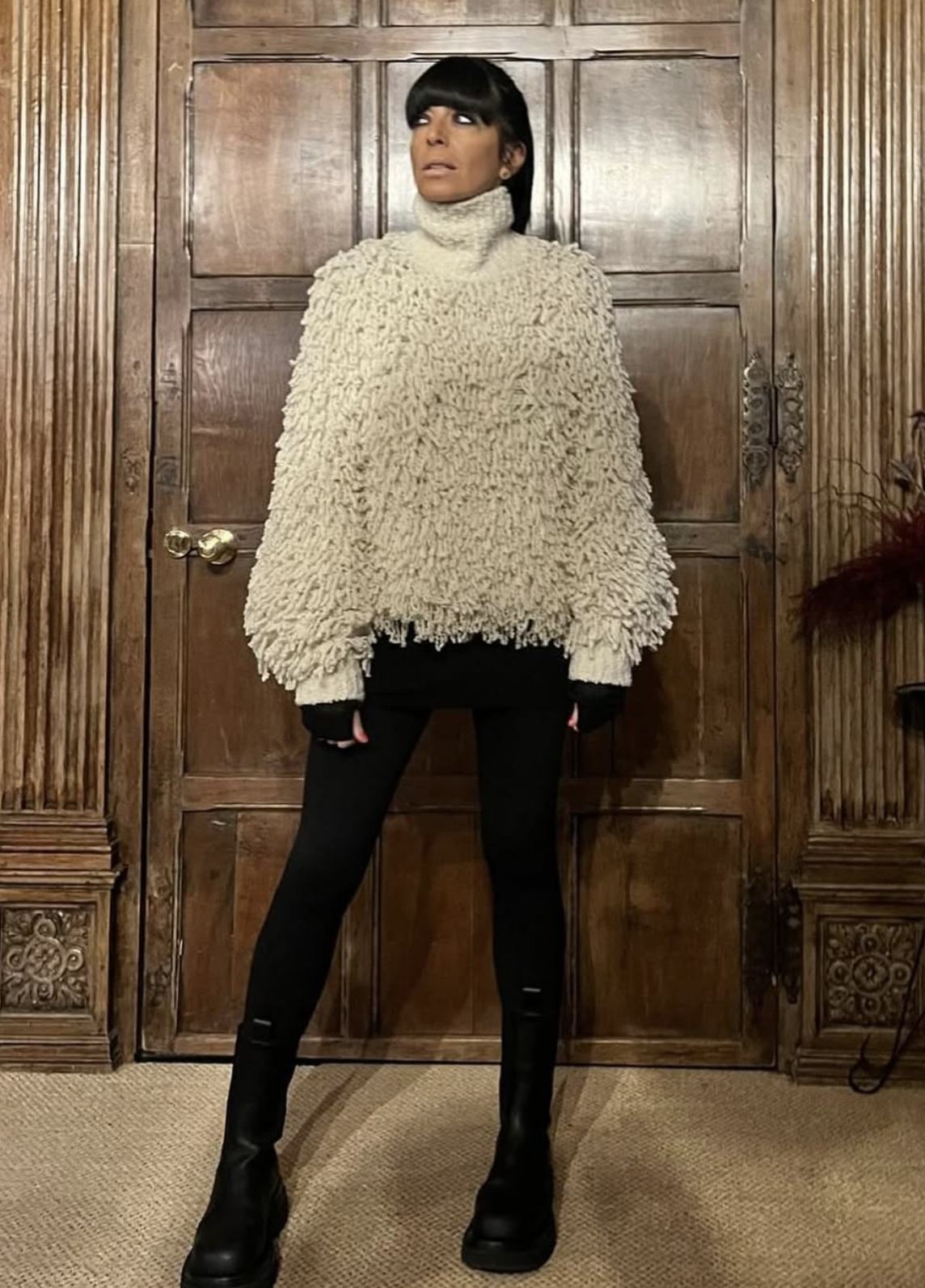 Claudia WInkleman wearing a cream fluffy jumper, black leggings and black coat.