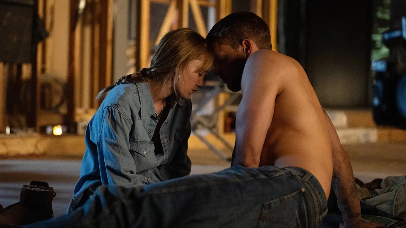 A blonde woman (Maika Monroe) sits with a shirtless man (Tyriq Withers) in a half-built construction site, in the movie adaptation of Colleen Hoover's book 'Reminders of Him.'