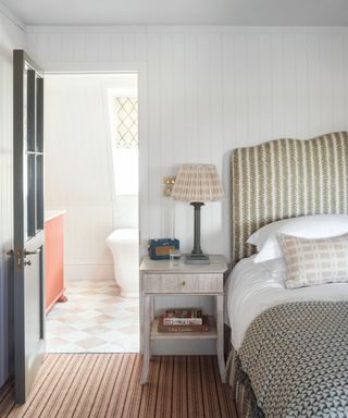 neutral bedroom with shiplap panel walls and a door painted green looking into the ensuite bathroom with checkerboard floor tiles