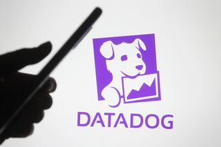Somebody using their phone in front of the Datadog logo