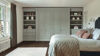 bedroom with fitted wardrobes painted in grey with large bed and pink soft cushions on bed