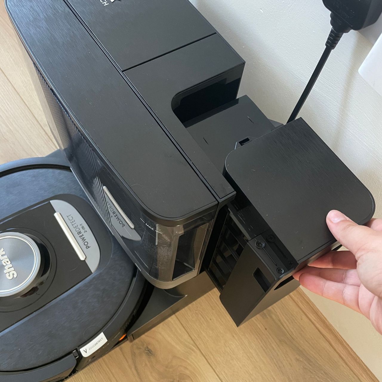 Hand pulling out the debris container of the Shark PowerDetect NeverTouch Robot Vacuum and Mop