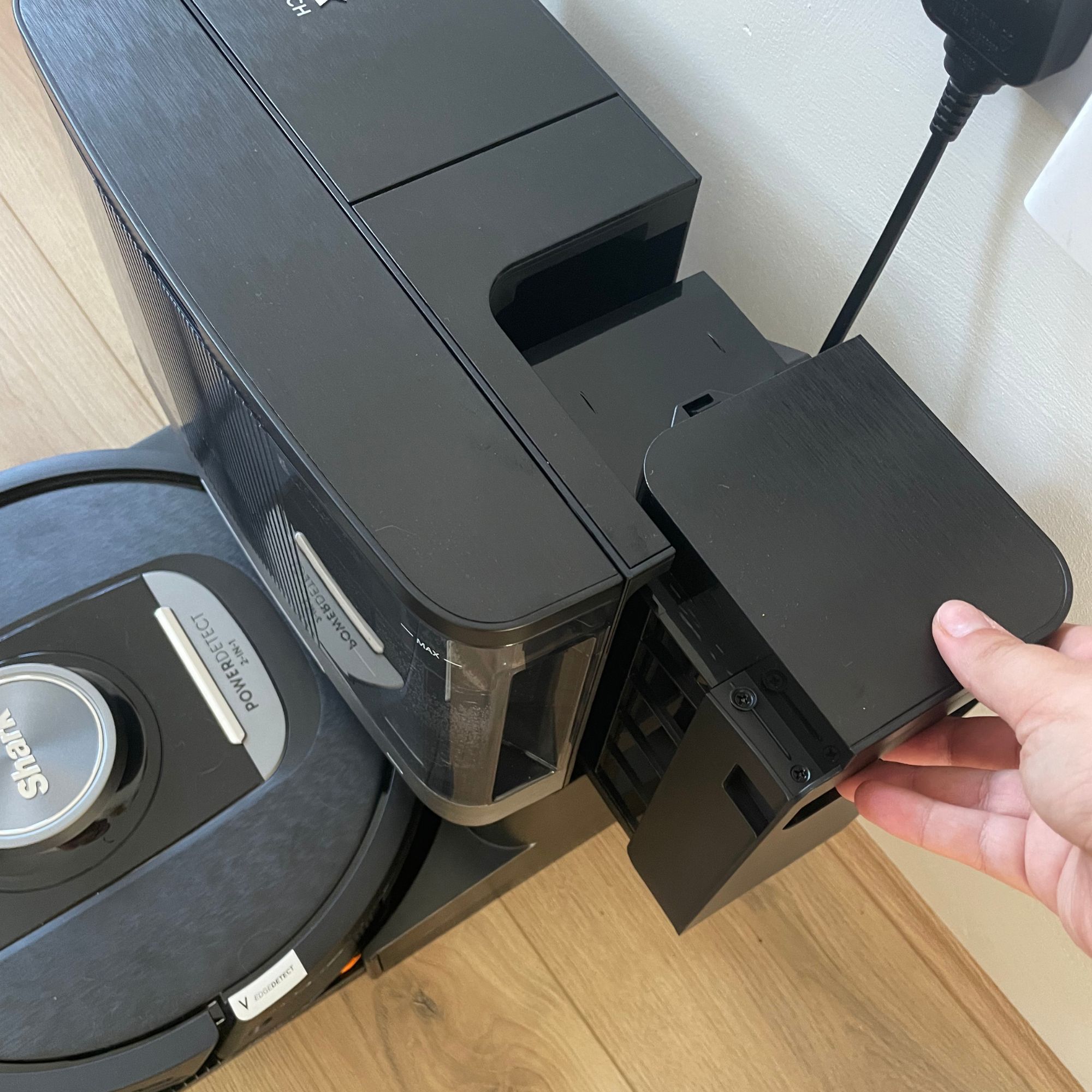 Hand pulling out the debris container of the Shark PowerDetect NeverTouch Robot Vacuum and Mop