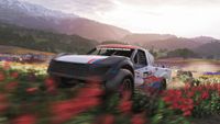 Forza Horizon 6: Several off-road vehicles, including a jeep centre-frame, racing through a field of red flowers.