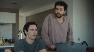 From left to right: Cory Michael Smith sitting and looking forward and Ramy Youssef standing next to him in Mountainhead. 