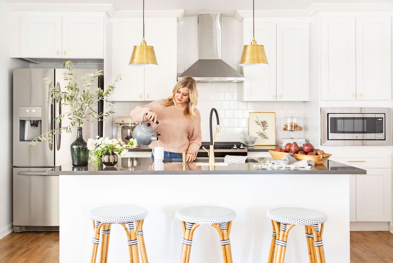 Kitchen styling in a white kitchen with a woman pouring hot water from a kettle